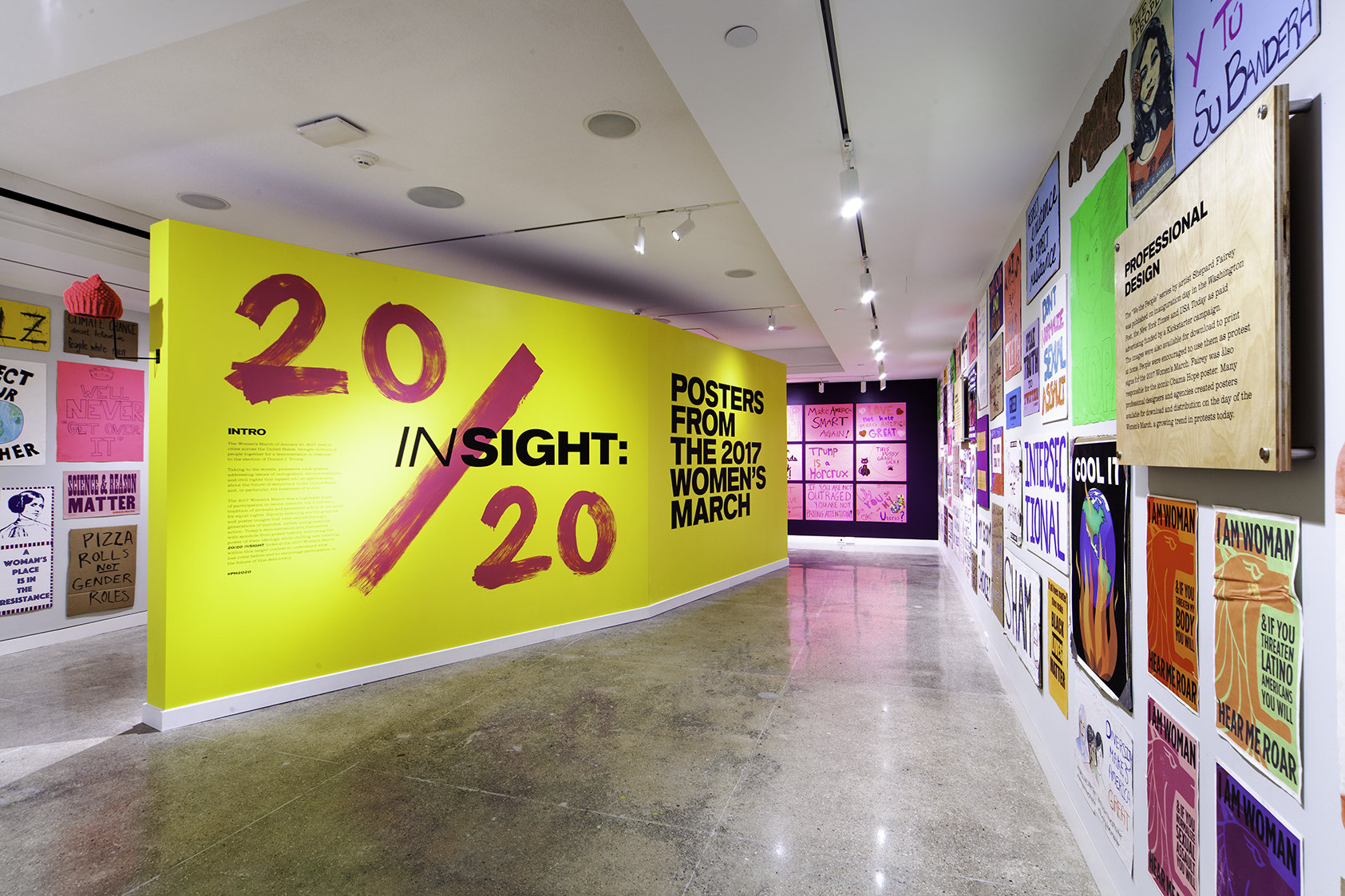 A yellow freestanding wall with pink and black text welcomes the guest into the mostly handwritten poster show.