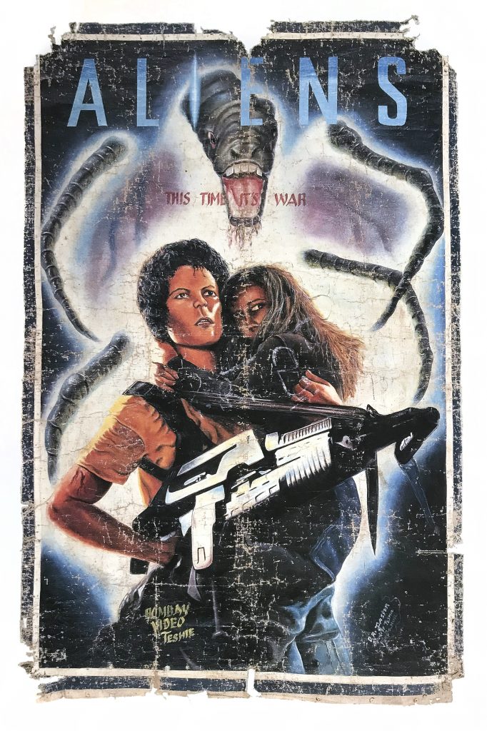 A movie poster of a kid hugging a woman with a large gun while an alien creature is behind them.