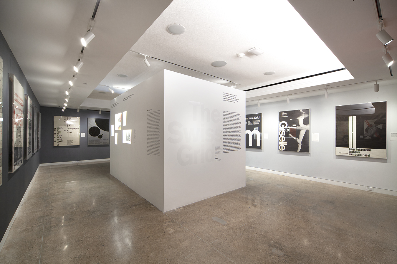 The Swiss Grid gallery viewing space with white and gray walls and black and white framed posters with clean, clear text.