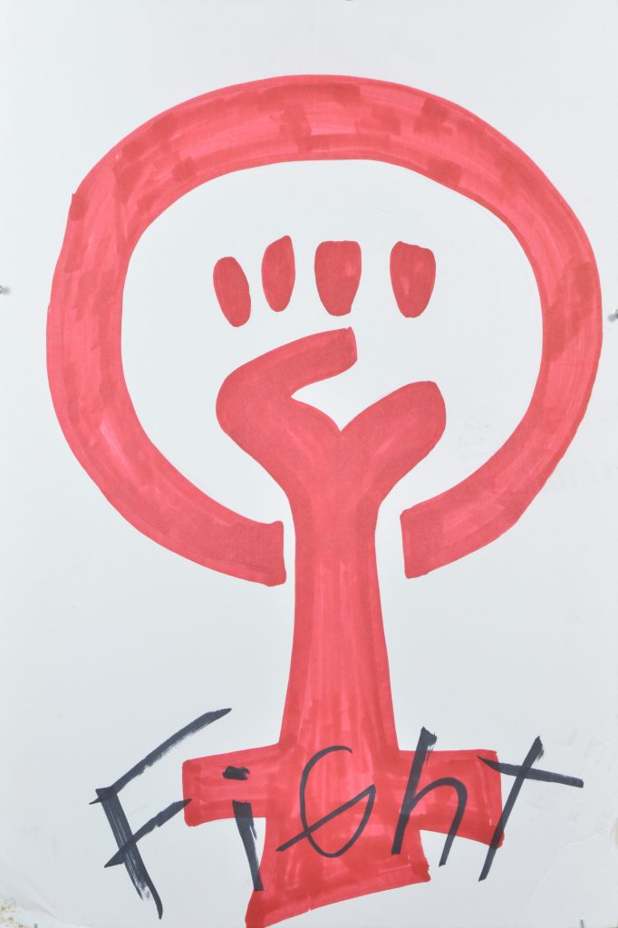 A poster of a red hand drawn feminism symbol and hand written text.