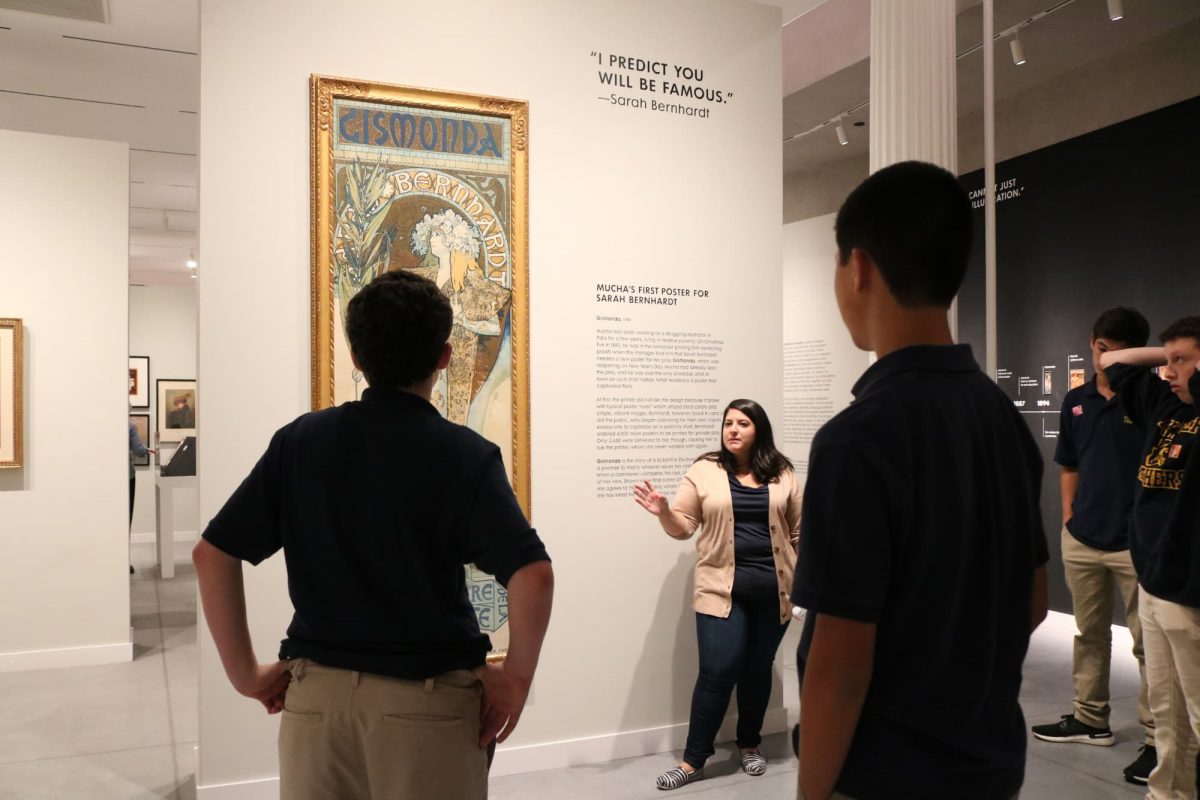 photograph of a group of students and an educator standing in front of a poster