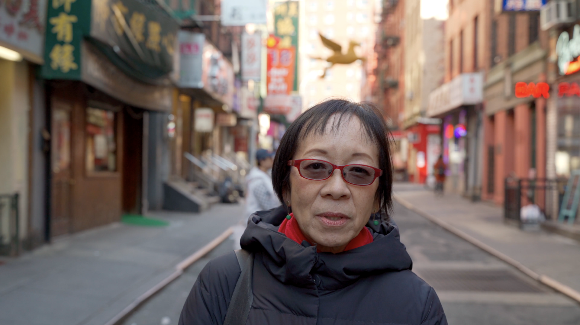 An asian woman with short hair standing on a Chinatown street.