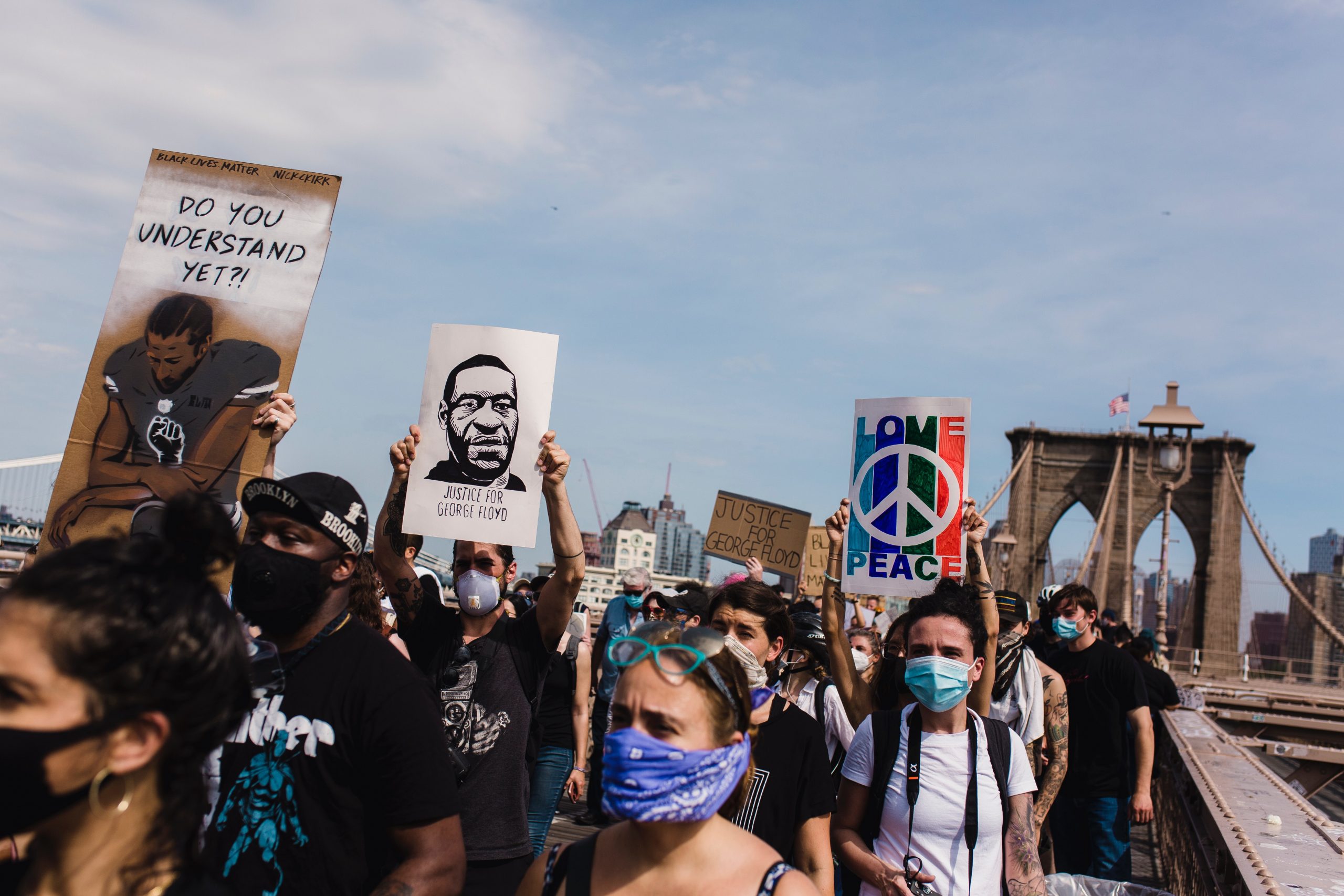 Protestors for the Black Lives Matter movement cross the Brooklyn Bridge holding a sign of Colin Kapernick asking,