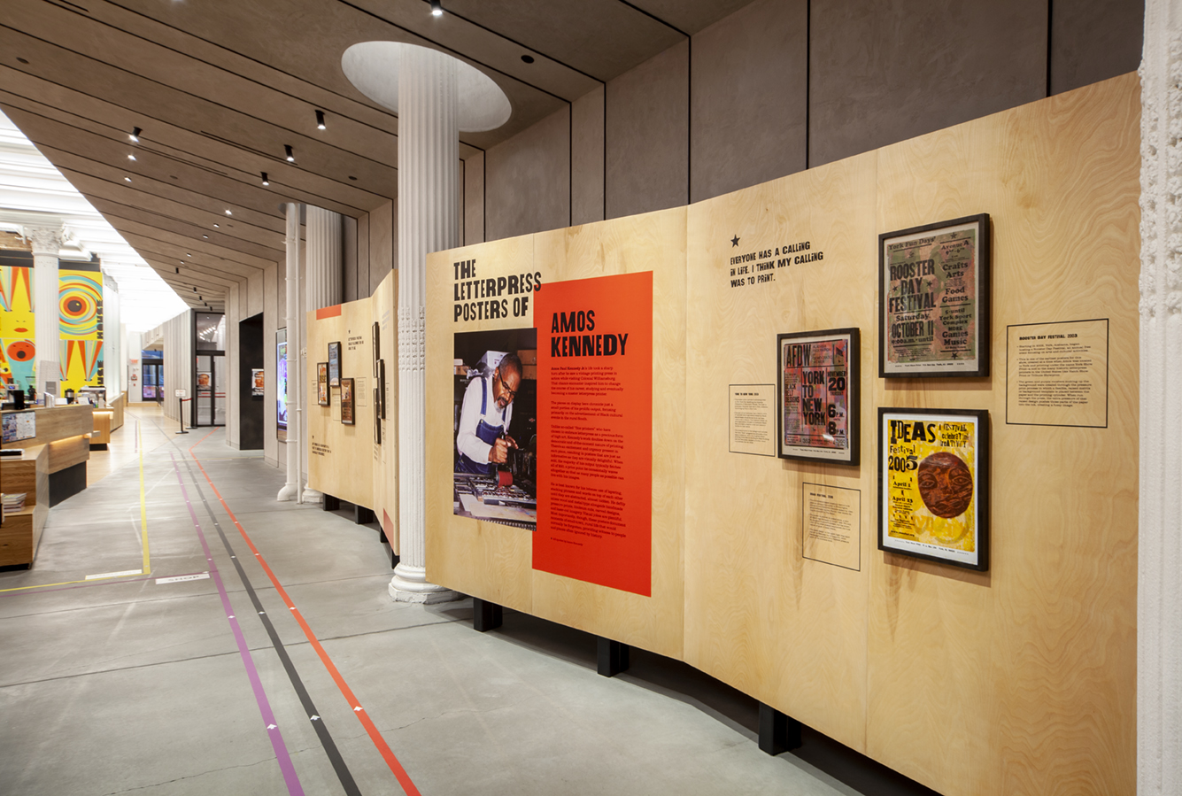 Plywood freestanding walls showcasing letterpress posters and an inlaid photo of Amos Kennedy.