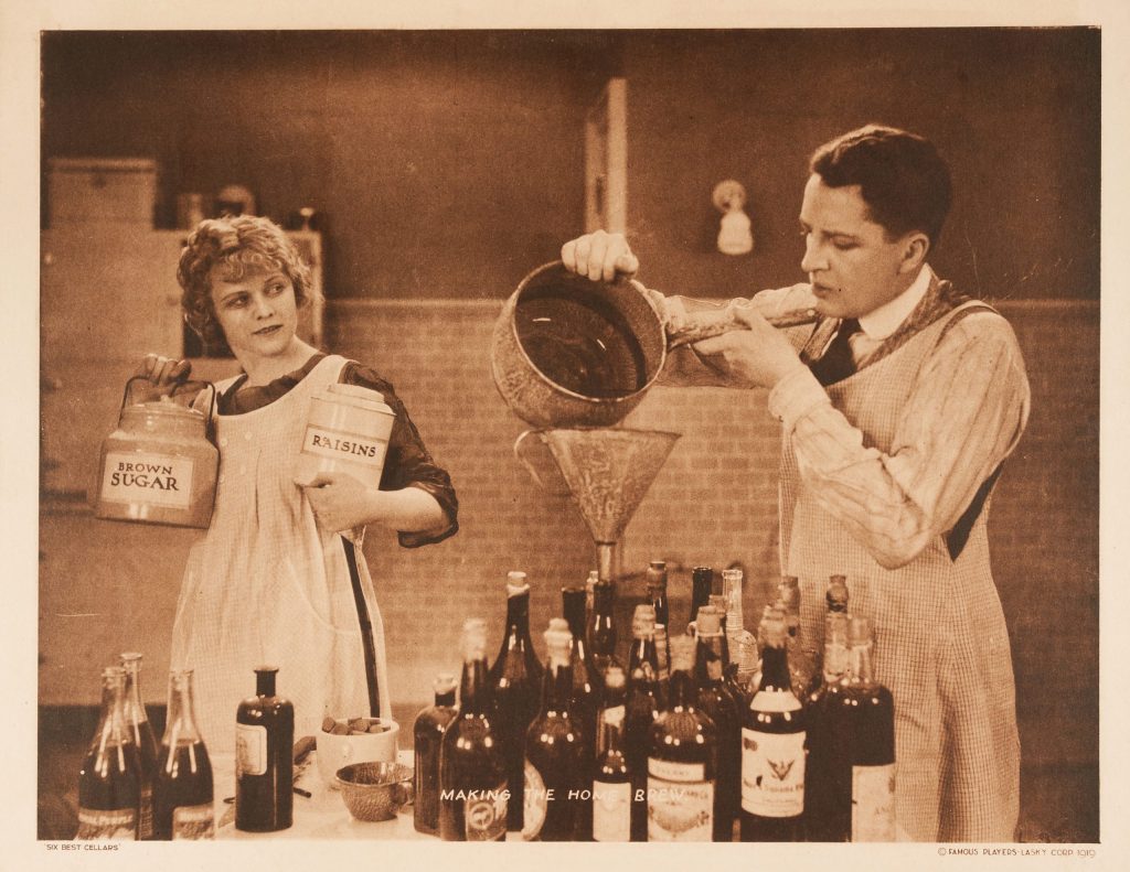 A lobby card of a couple pouring liquid into a variety of empty bottles of alcohol.