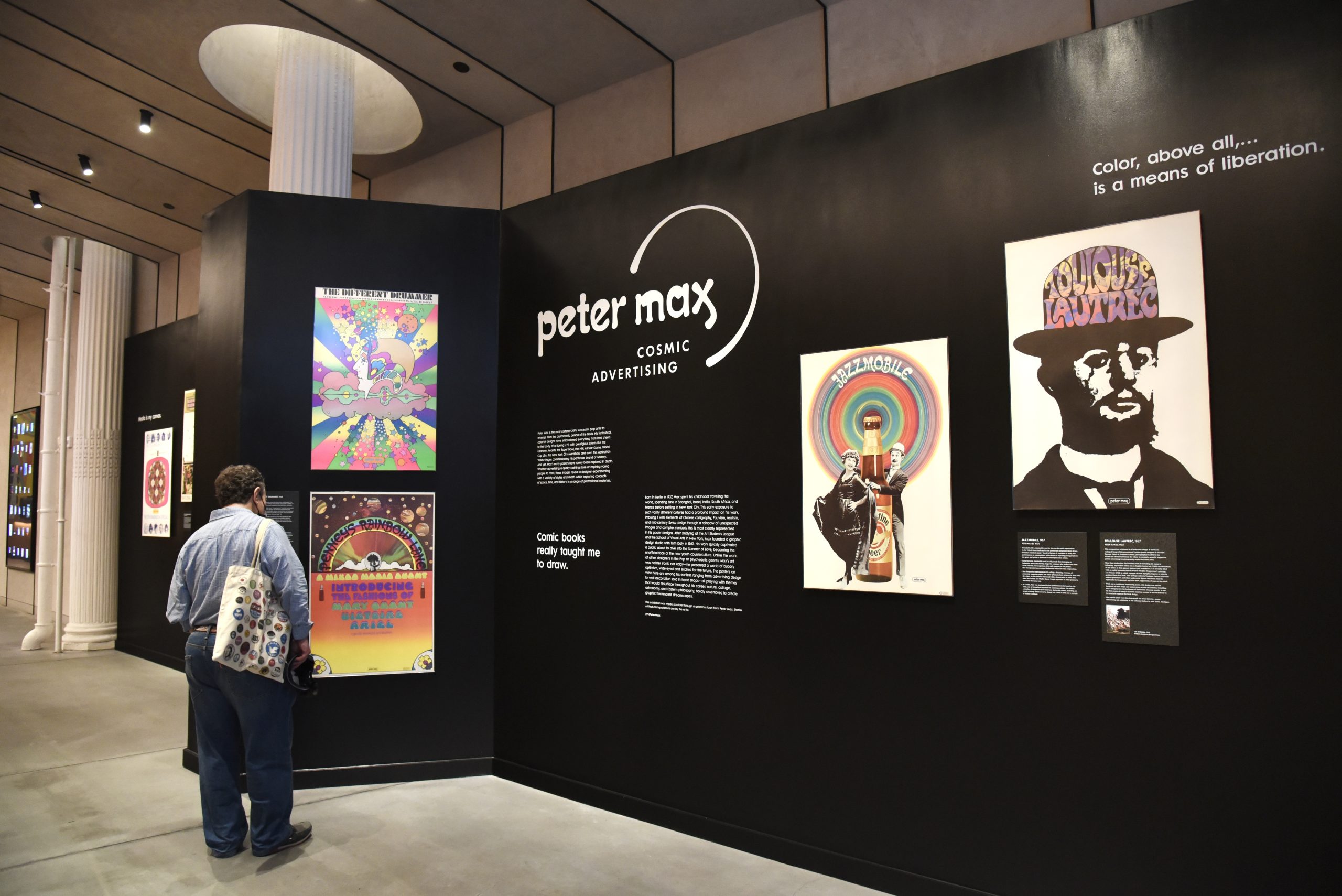 A visitor enjoying an assortment of psychedelic posters on a black gallery wall.