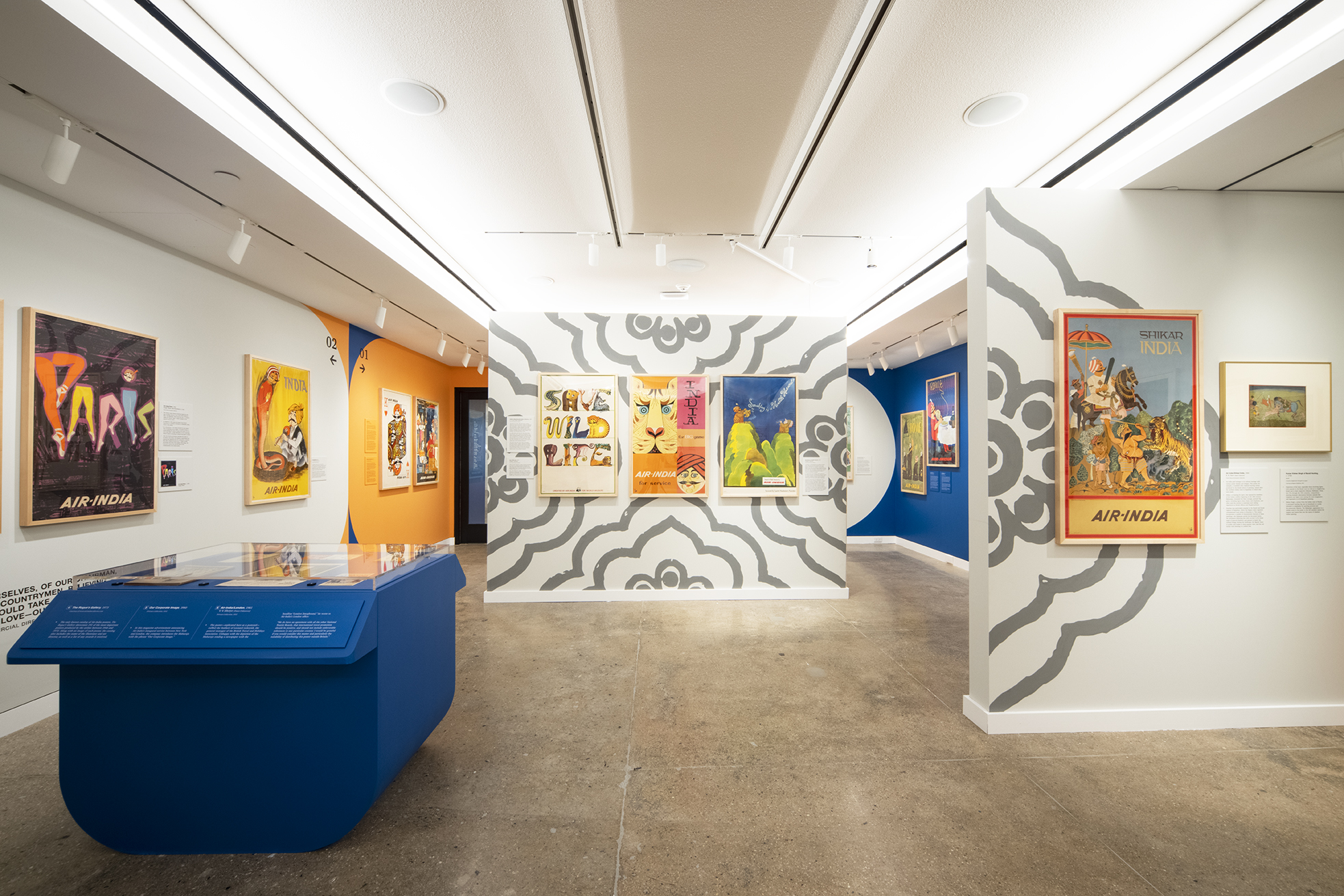 Air-India framed posters on gallery walls. On the left there is a blue, rounded display case of printed ephemera.