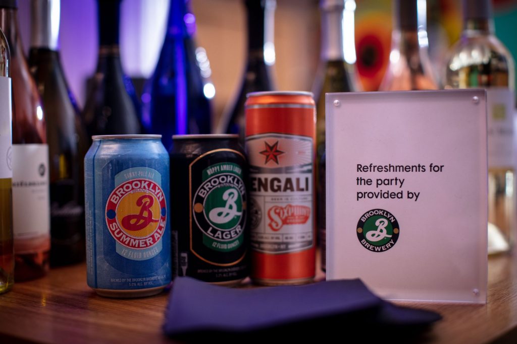 Cans of beers on a counter with bottles of wine in the background.