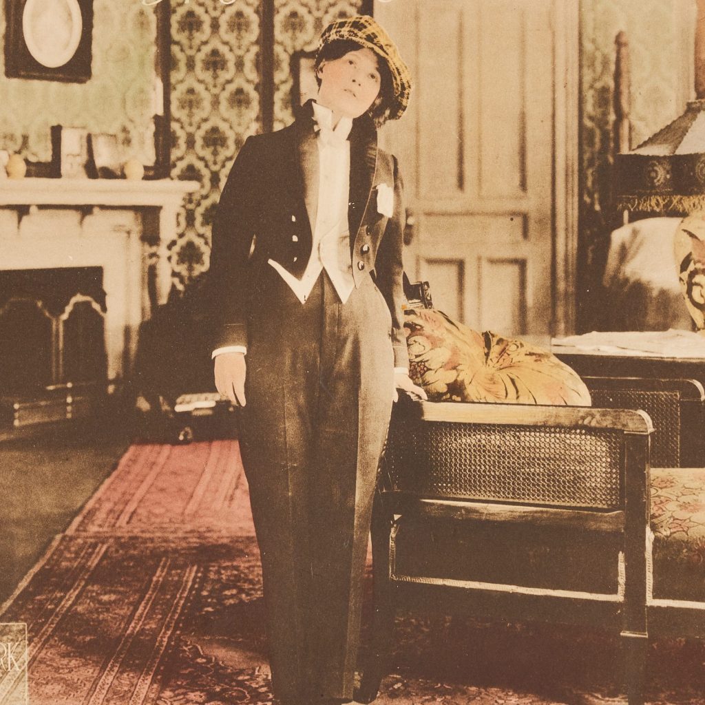 photographic image of a woman in a men's tuxedo in a lavish living room