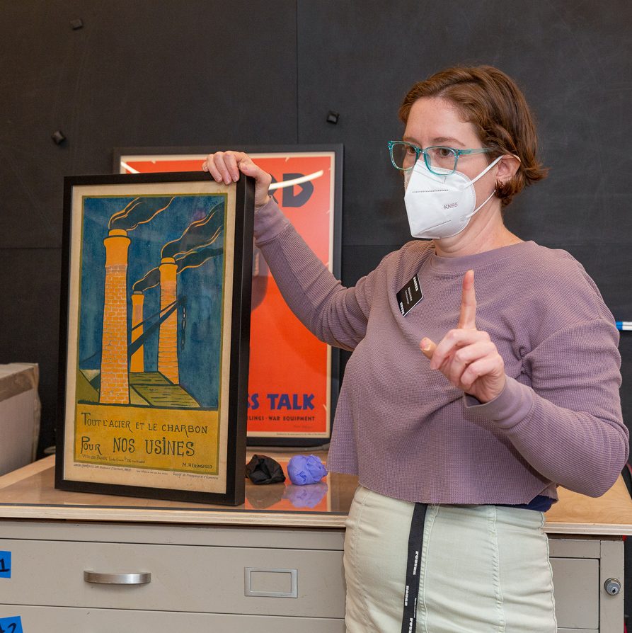 An image of a person standing with a framed poster image.