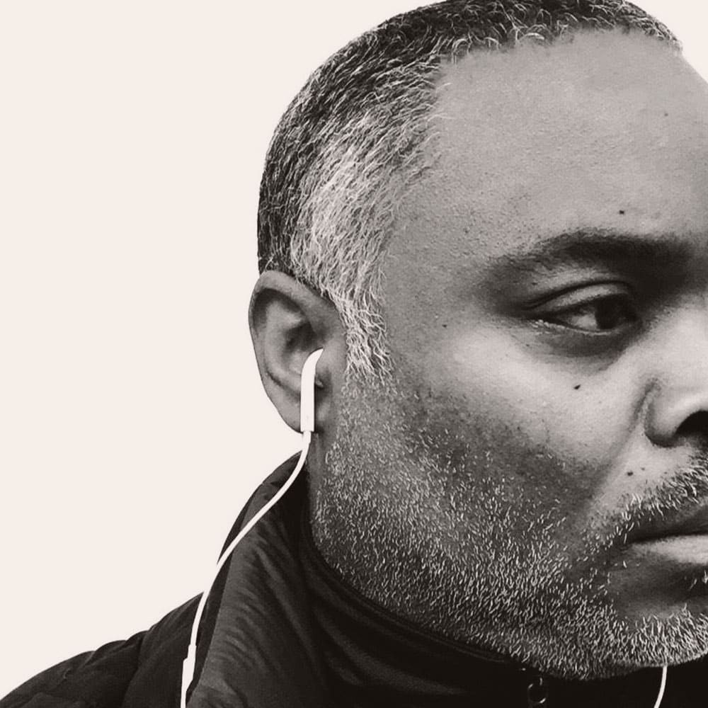 a black and white headshot of a man with headphones in his ear