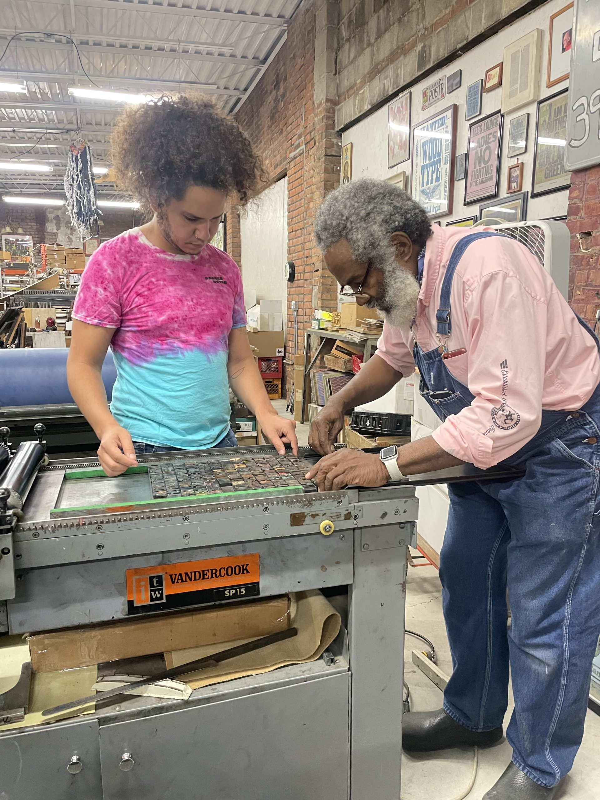 Photograph of two people working on a press bed.