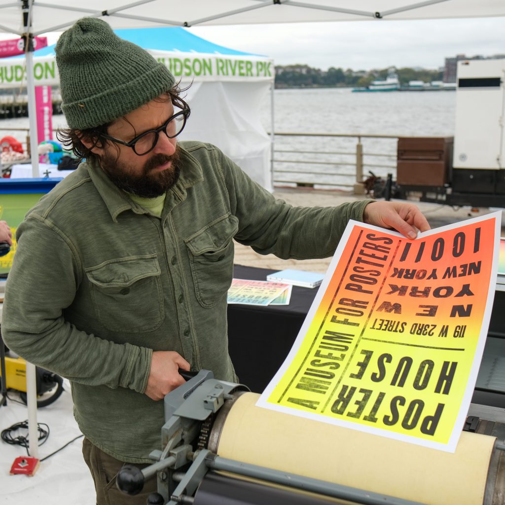 a photograph of a man pulling a letterpress poster.