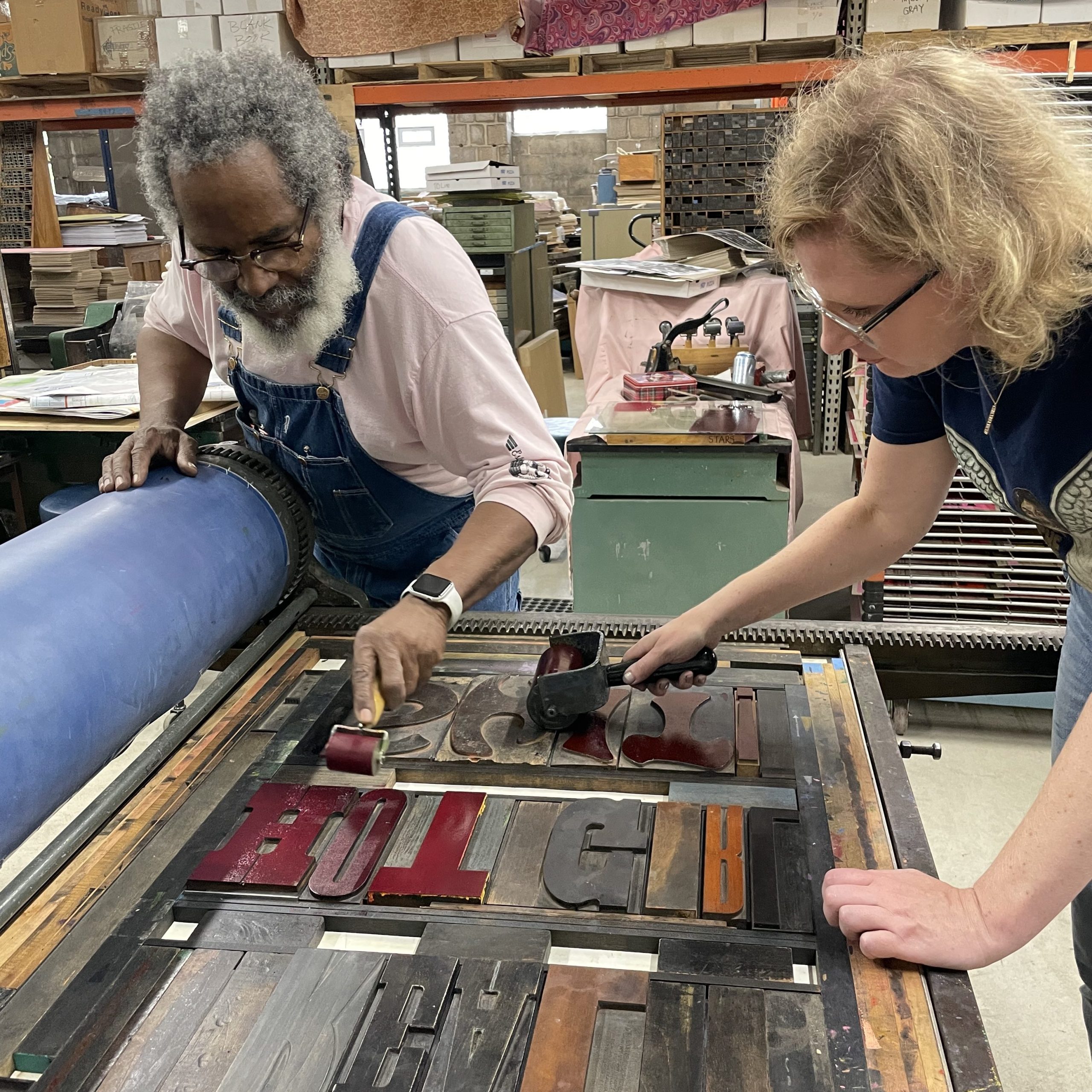 Photograph of two people braying on a large press.