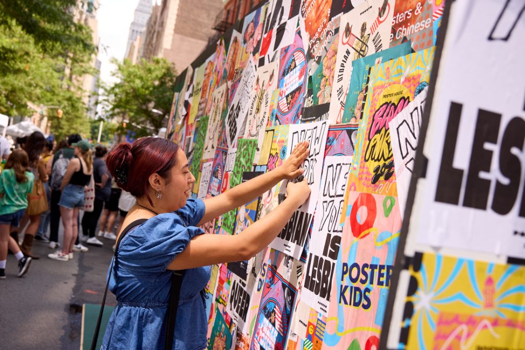 A photo of a woman placing a poster on a wall