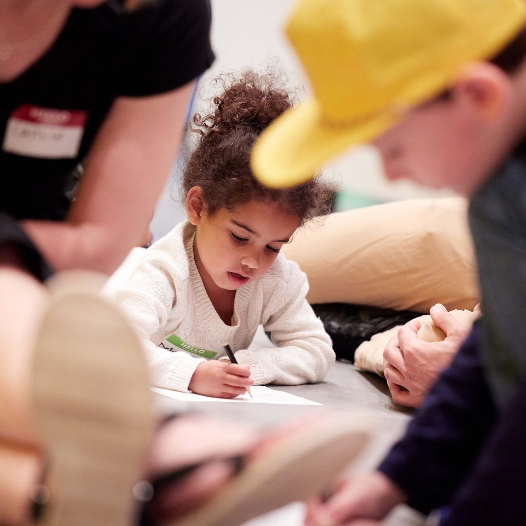 A photo of a child writing on a piece of paper in a museum