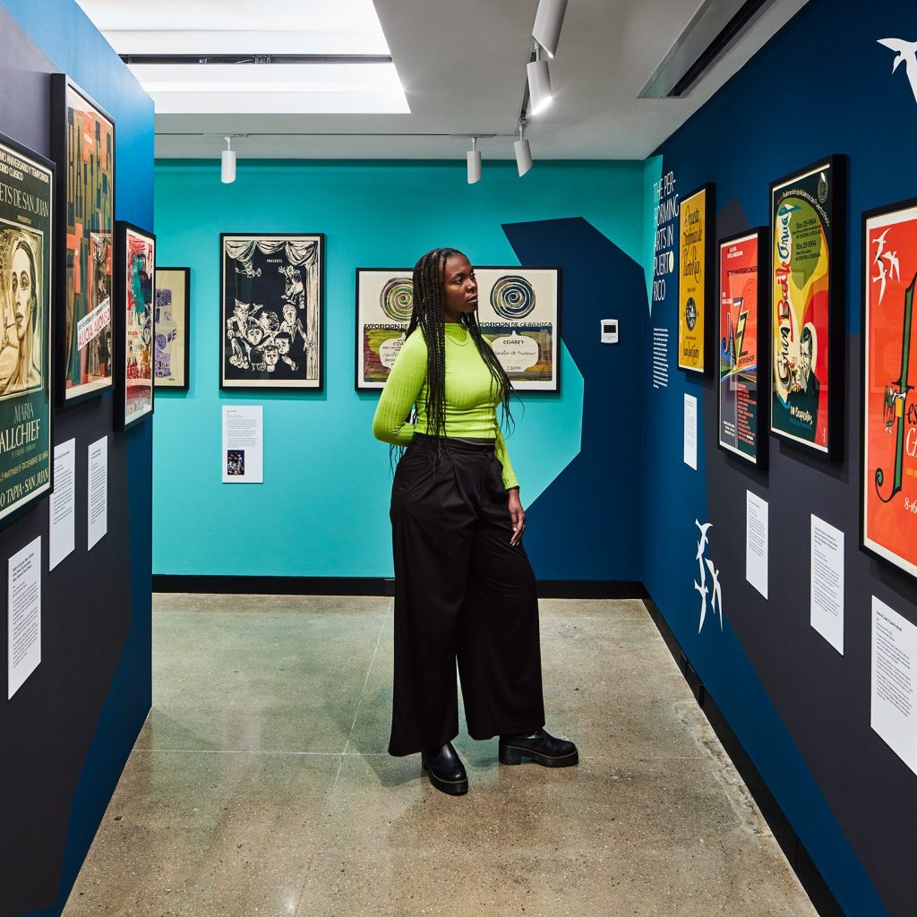 A woman looks at a poster on the wall in an art gallery