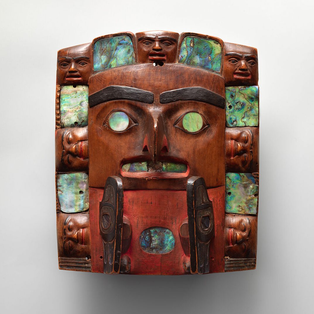 A square, wooden sculpture of a face.